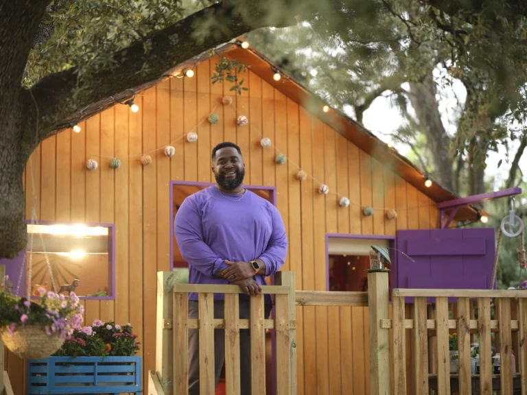 A smiling man standing on the porch of a home